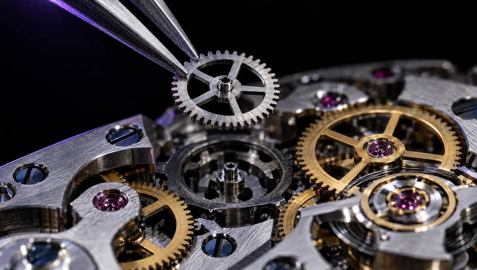 Close-up of a watch movement: tweezers place a steel wheel among gold gears and ruby jewels.